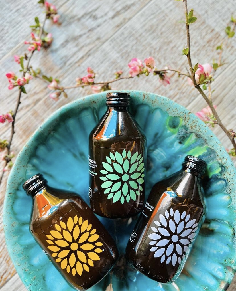 Three Now O'Clock kombucha flavours in a teal bowl with blossoms